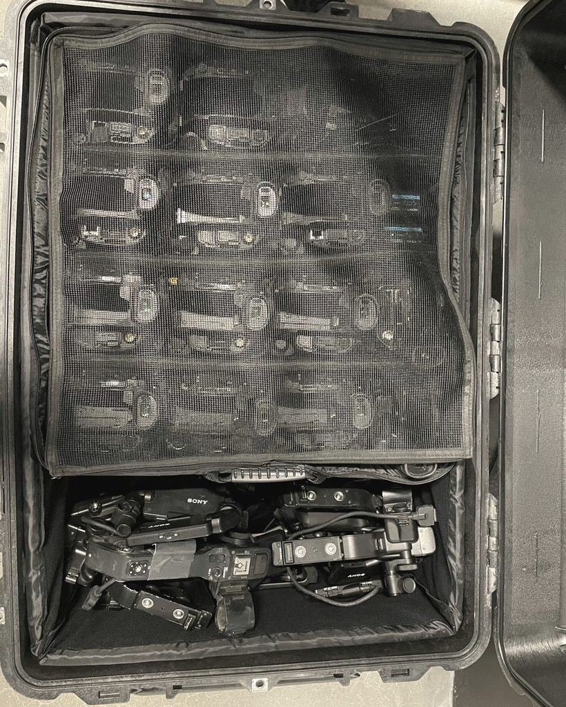 A hard case packed with rows of netted camera bodies and a folded gimbal rig